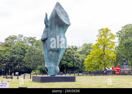 Londra, Inghilterra - 1 giugno 2024: Statua della testa di cavallo nel parco vicino a Hyde Park Achilles Way. Fogliame di alberi e sfondo stradale. Persona visibile sulla strada. Foto Stock