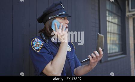 Un agente di polizia parla al telefono mentre tiene un taccuino in una strada della città. Foto Stock