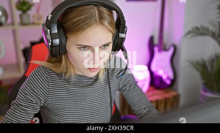 Donna bionda con cuffie che gioca in una stanza colorata di notte Foto Stock