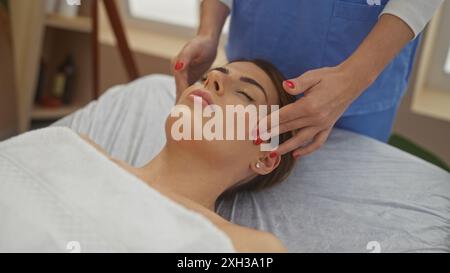 Una donna che riceve un massaggio rilassante da un terapeuta in un centro benessere, che presenta un ambiente spa interno sereno con particolare attenzione alla bellezza e alla rela Foto Stock