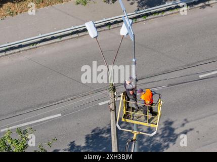 I lavoratori che installano su un sollevatore pneumatico per auto stanno installando una nuova lampada stradale. Foto Stock