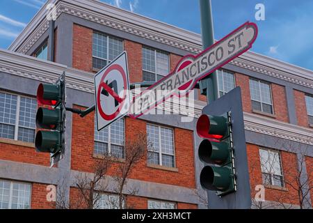 Semaforo rosso con cartello stradale di San Francisco, segnale direzionale impostato prima dell'edificio in mattoni in tarda serata Foto Stock