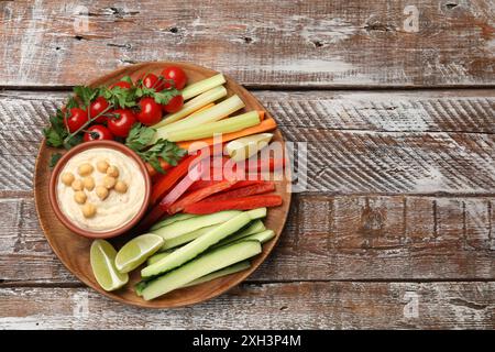 Gustoso hummus fatto in casa con ceci e verdure diverse su un tavolo di legno, vista dall'alto. Spazio per il testo Foto Stock