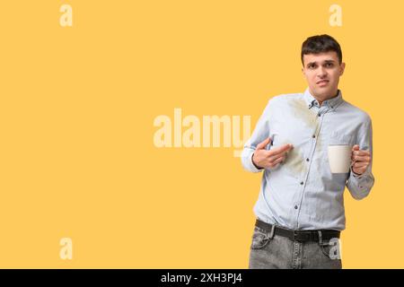 Giovane stressato con macchie di caffè sulla camicia su sfondo arancione Foto Stock