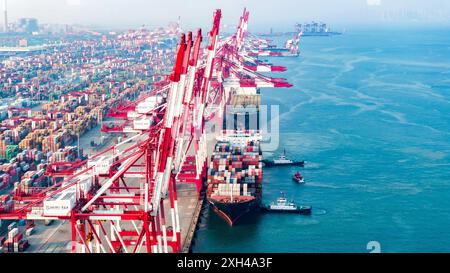 QINGDAO, CINA - 11 LUGLIO 2024 - i container sono caricati e scaricati presso il terminal container di Qianwan del porto di Qingdao, porto di Shandong, Cina, 11 luglio, Foto Stock