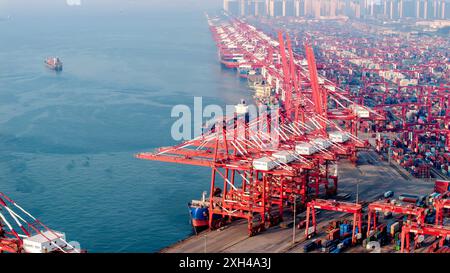 QINGDAO, CINA - 11 LUGLIO 2024 - i container sono caricati e scaricati presso il terminal container di Qianwan del porto di Qingdao, porto di Shandong, Cina, 11 luglio, Foto Stock