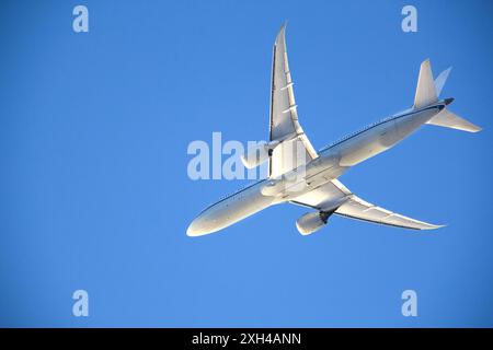 Vista dal lato inferiore dell'aereo commerciale che vola attraverso il cielo azzurro Foto Stock