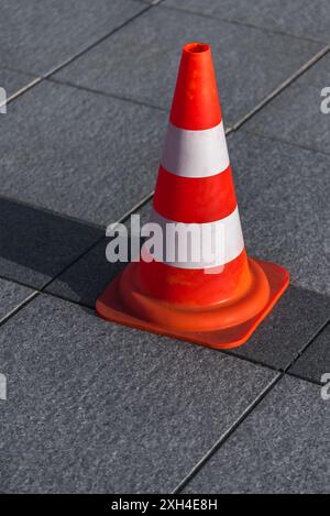 Cono di traffico in piedi su marciapiedi piastrelle di granito Foto Stock