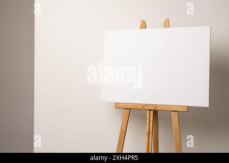 Una tela vuota poggia su un cavalletto di legno su uno sfondo neutro, con spazio di copia. Ideale per gli artisti per mostrare la loro creatività, questo setup invit Foto Stock