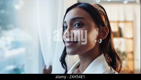 Donna indiana, sorriso o finestra in casa con pensiero o positivo, idea o pianificazione per il lavoro. Insegnante donna, vetro o casa con riflessione per l'inverno Foto Stock