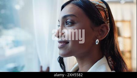 Donna indiana, felice o finestra in casa con pensiero o positivo, idea o pianificazione per il lavoro. Insegnante donna, vetro o casa con riflessione per l'inverno Foto Stock