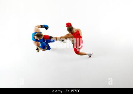 Vista aerea dinamica di due pugili, catturando il pugno rosso rivolto all'avversario blu su sfondo bianco dello studio. Foto Stock
