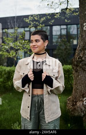 Una giovane donna si erge graziosamente di fronte a un albero torreggiante, che si collega con la natura. Foto Stock