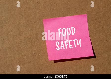 Messaggio di sicurezza alimentare scritto su carta rosa con sfondo in cartone. Simbolo concettuale di sicurezza alimentare. Copia spazio. Foto Stock