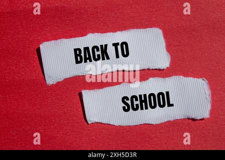 Messaggio di ritorno a scuola scritto su carta bianca strappata con sfondo rosso. Simbolo concettuale di ritorno a scuola. Copia spazio. Foto Stock