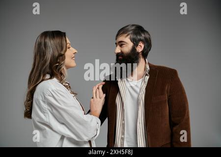 Una coppia con un abbigliamento sofisticato sta in piedi vicino, la donna poggia delicatamente la mano sulla spalla di mans. Foto Stock