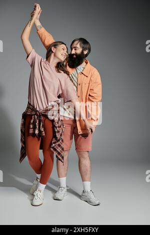 Una coppia posa in uno studio, la donna che tiene per mano i mans mentre ballano insieme, sorridendo e guardandosi. Foto Stock