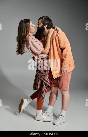 Un paio si pone affettuosamente, l'uomo che tiene vicino il suo partner in un abbraccio amorevole. Sono entrambi elegantemente vestiti con un abbigliamento moderno. Foto Stock