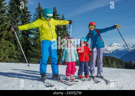 Famiglia di quattro sciatori su piste innevate che si allungano felicemente le mani Foto Stock