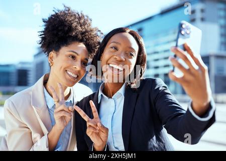 Diverse donne d'affari che portano Selfie in ambientazione urbana, celebrando il successo e l'amicizia Foto Stock