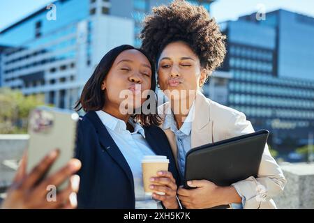 Imprenditori diversi che realizzano un selfie in un ambiente urbano con caffè e laptop Foto Stock