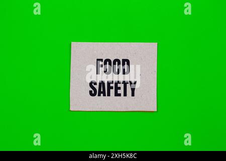 Messaggio di sicurezza alimentare scritto su un pezzo di carta con sfondo verde. Simbolo concettuale di sicurezza alimentare. Copia spazio. Foto Stock