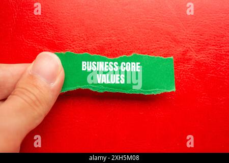 Messaggio Business Core Values scritto su un foglio verde strappato con sfondo rosso. Simbolo dei valori fondamentali aziendali concettuali. Copia spazio. Foto Stock