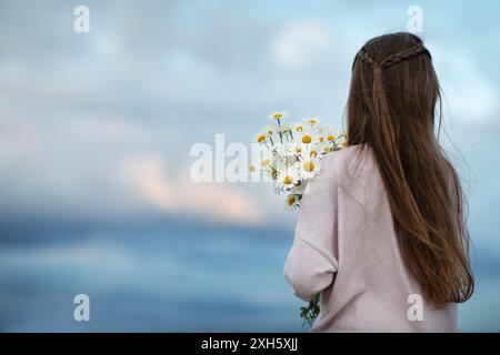 Girl with a bouquet of white daisies flowers on her shoulder outdoors Stock Photo