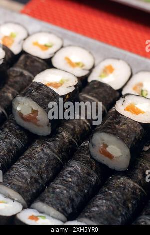 Una varieta' di sushi roll disposti ordinatamente su un vivace tavolo rosso, che mostra un variegato e appetitoso assortimento di cucina Giapponese Foto Stock