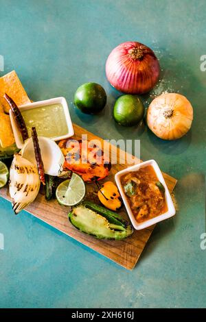 Assorted grilled vegetables, dips, and fresh ingredients on a board. Foto Stock