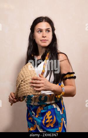 Giovane donna che indossa abiti africani tradizionali che tiene un fan intrecciato in posa per la macchina fotografica Foto Stock