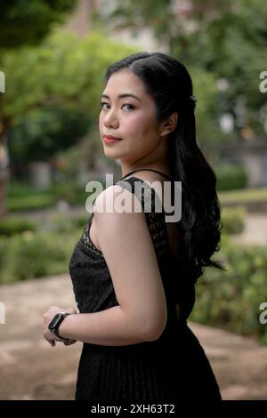 An Asian lady with long black hair, wearing black dress outdoors Stock Photo