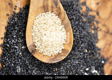 sesamum, sesamo (Sesamum indicum), semi di sesamo sbucciati e non sbucciati con cucchiaio di legno Foto Stock