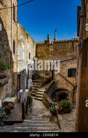 Pitigliano, Grosseto, Toscana, Italia - 27 aprile 2024 - Uno scorcio dell'antico borgo medievale conosciuto come la piccola Gerusalemme. Un vicolo stretto con t Foto Stock