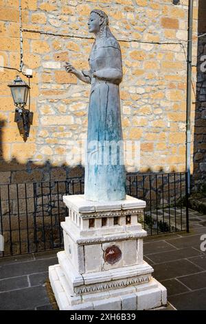 Pitigliano, Grosseto, Toscana, Italia - 27 aprile 2024 - Uno scorcio dell'antico borgo medievale conosciuto come la piccola Gerusalemme. La statua di marmo, mo Foto Stock