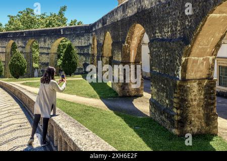 Donna sola che scatta una foto con uno smartphone all'acquedotto di San Sebastian (Sao Sebastiao o Arcos do Jardim) nella città di Coimbra, Portogallo, Europa Foto Stock