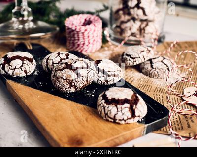 Un primo piano di biscotti natalizi incrinati su una tavola di legno con decorazioni natalizie sullo sfondo Foto Stock