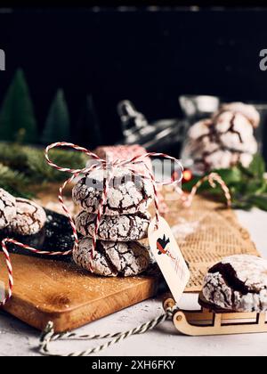 Una pila di biscotti natalizi incrinati con zucchero a velo su una tavola di legno, decorata con un nastro festivo e un cartellino, sullo sfondo delle vacanze. Foto Stock
