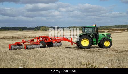 Trattore sul campo con impacchettamento del terreno King Roller nelle giornate di sole Foto Stock