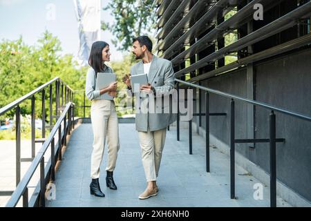 Uomo d'affari e donna fuori dall'ufficio con un notebook e un tablet digitale. Tecnologia utilizzata nella moderna vita imprenditoriale. Gli esperti di energia sostenibile devono Foto Stock