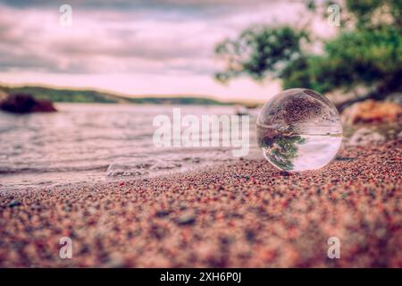 Primo piano di una sfera di cristallo sulla sabbia in spiaggia contro il cielo Foto Stock