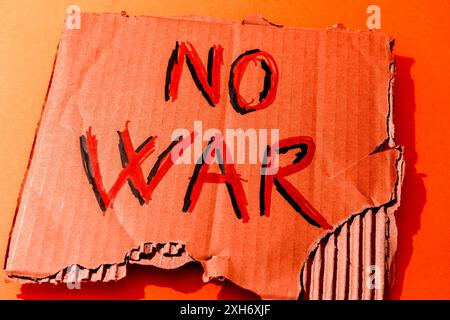 Pezzo di cartone con le parole "NO WAR" scritte su sfondo rosso Foto Stock