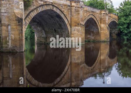 Una vista panoramica del fiume Tees a Yarm, Inghilterra, Regno Unito, che mostra il ponte stradale e le rive alberate del fiume con riflessi sull'acqua Foto Stock