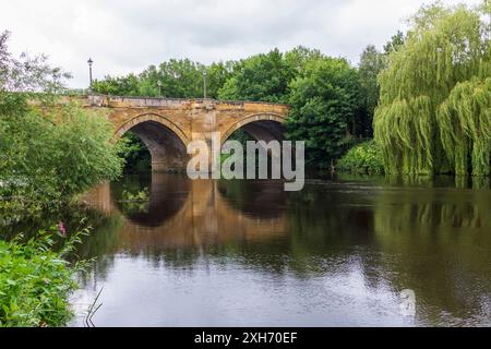 Una vista panoramica del fiume Tees a Yarm, Inghilterra, Regno Unito, che mostra il ponte stradale e le rive alberate del fiume con riflessi sull'acqua Foto Stock