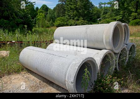 Sei sezioni di tubi di scarico in calcestruzzo impilate in un'area erbosa Foto Stock