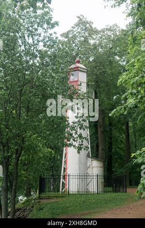 vecchio faro sulla riva del mare tra gli alberi Foto Stock