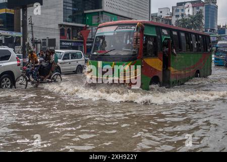 Dacca, Bangladesh. 12 luglio 2024. Un risciò e un autobus si spostano attraverso una strada di Dhaka bagnata da forti piogge che causano molta sofferenza ai pedoni e ai pendolari. La pioggia monsonica nella città di Dacca, la forte pioggia monsonica ha causato un disboscamento d'acqua estremo nella maggior parte delle aree della città di Dacca. Le strade erano sommerse rendendo la marcia lenta e pericolosa. Credito: SOPA Images Limited/Alamy Live News Foto Stock