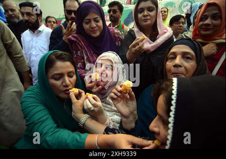 Gli attivisti di Tehreek-e-Insaf (PTI) stanno organizzando manifestazioni celebrative e distribuendo dolci tra loro dopo la decisione della corte suprema a loro favore, alla Insaf House di Karachi venerdì 12 luglio 2024. Venerdì la Corte Suprema del Pakistan ha ribaltato la negazione dei seggi riservati al Consiglio sunnita Ittehad (SIC) appoggiato dal PTI, aprendo la strada a una grande vittoria legale per il partito di Imran Khan. Foto Stock