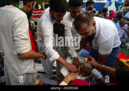 Gli attivisti di Tehreek-e-Insaf (PTI) stanno organizzando manifestazioni celebrative e distribuendo dolci tra loro dopo la decisione della corte suprema a loro favore, alla Insaf House di Karachi venerdì 12 luglio 2024. Venerdì la Corte Suprema del Pakistan ha ribaltato la negazione dei seggi riservati al Consiglio sunnita Ittehad (SIC) appoggiato dal PTI, aprendo la strada a una grande vittoria legale per il partito di Imran Khan. Foto Stock