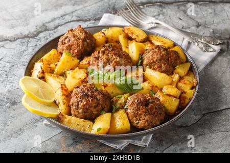 Polpettine di manzo bifteki al forno greco con patate al limone sul piatto sul tavolo. Orizzontale Foto Stock